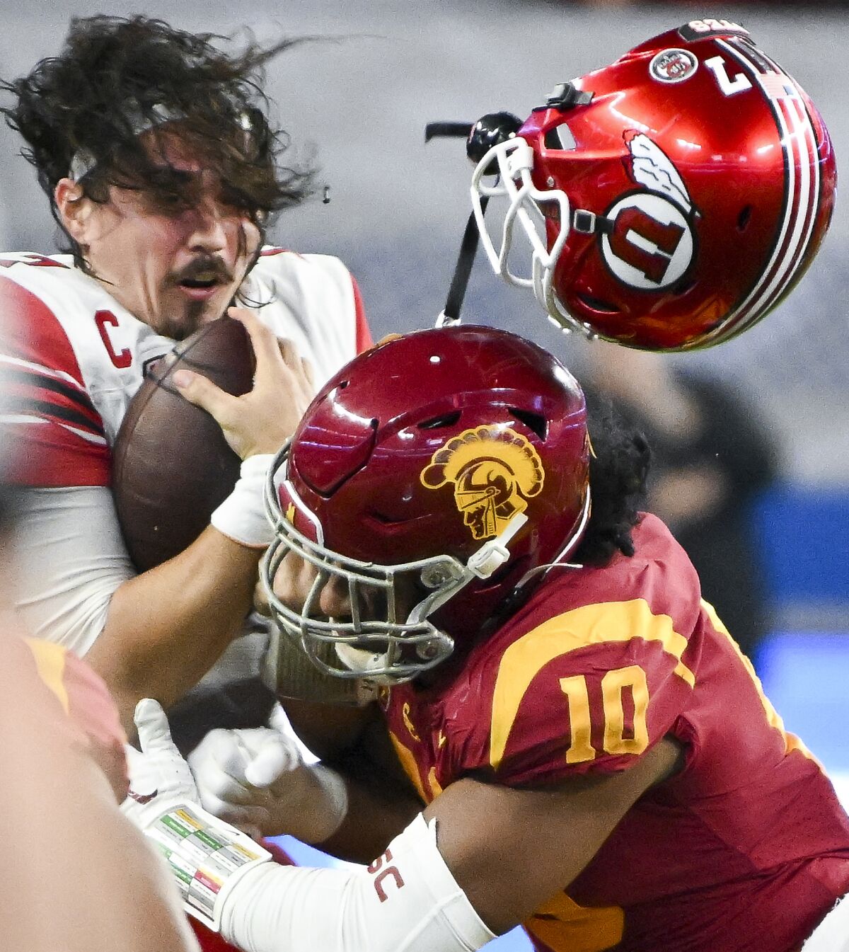 USC linebacker Ralen Goforth tackles Utah quarterback Cameron Rising, whose helmet popped off during the play