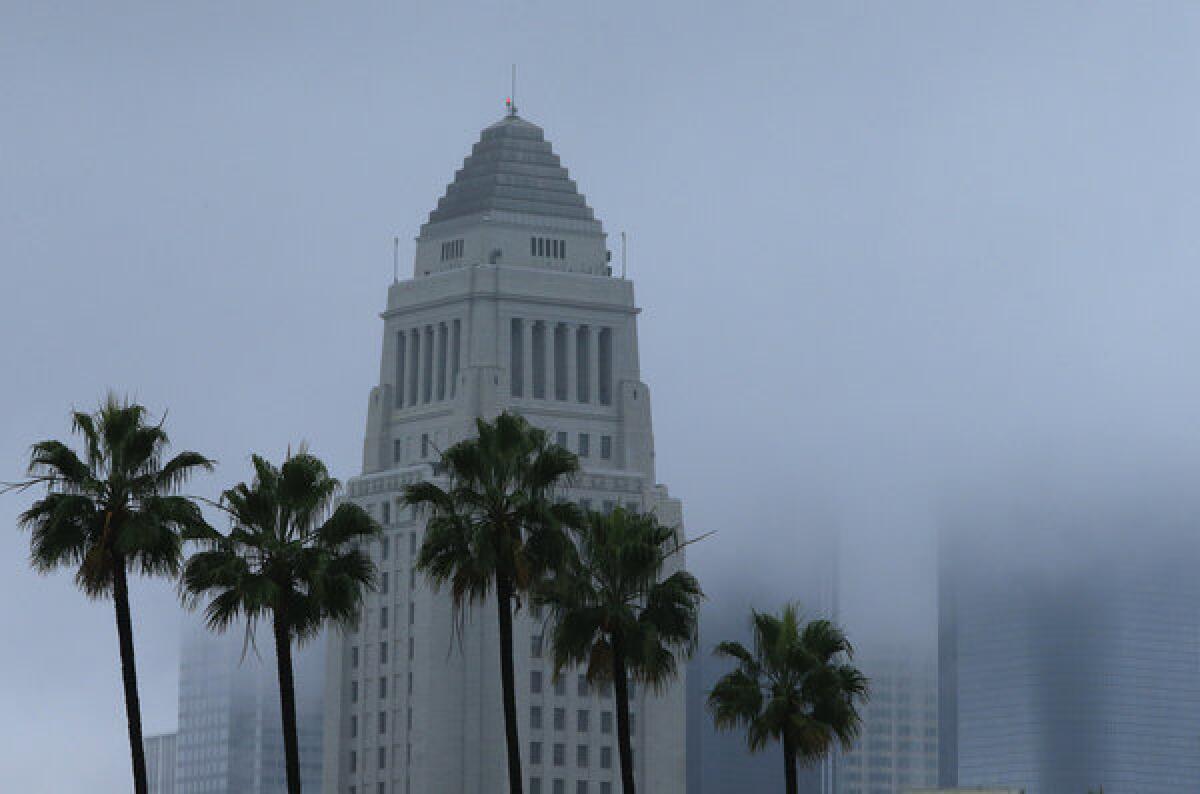 City Hall stands out in downtown Los Angeles as storm clouds obscure the other office towers Thursday.