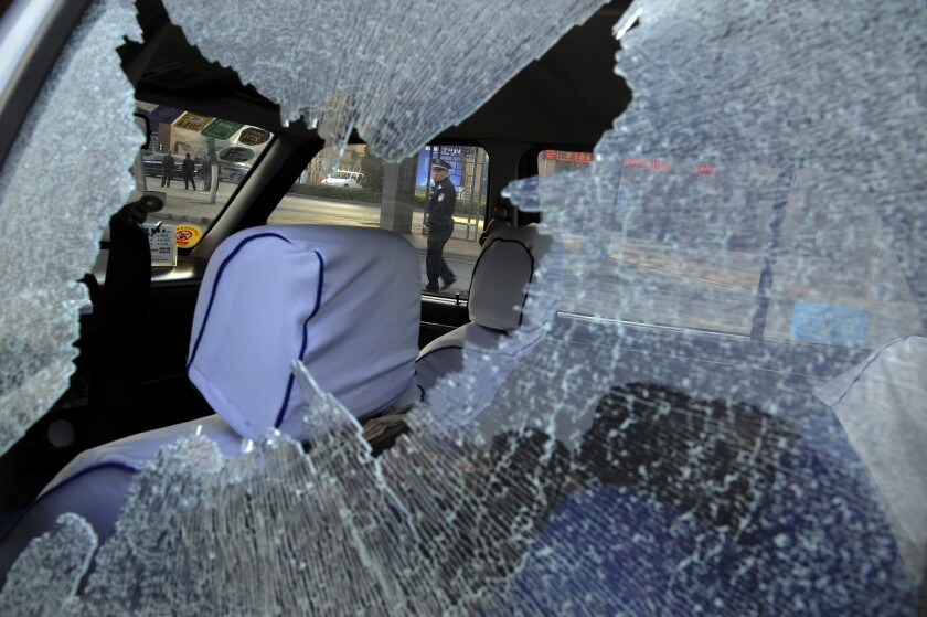 A Chinese police officer is framed by the shattered window of a vehicle damaged in a series of explosions at the Communist Party headquarters in the provincial city of Taiyuan.