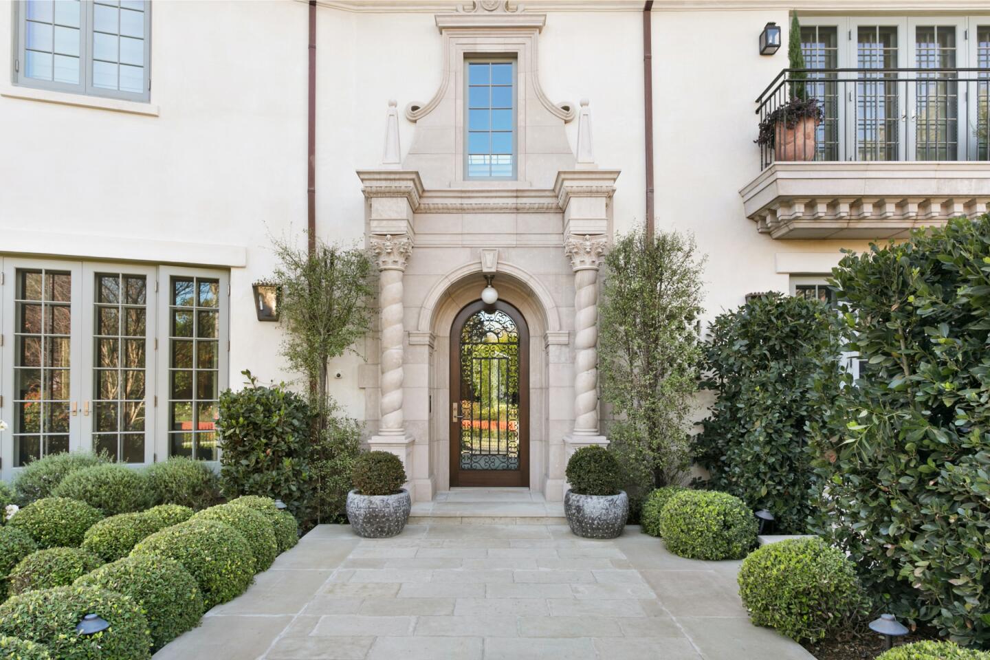 The entrance has a rounded top doorway and a walkway with shrubs on either side leading to it.