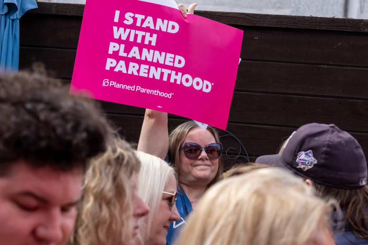 一名支持者举着标语，上面写着“我与计划生育协会站在一起”。