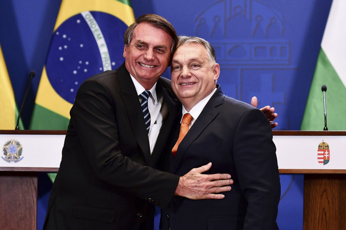 Hungarian Prime Minister Viktor Orban, right and Brazilian President Jair Bolsonaro hug each other at the end of a joint press statement at the Carmelite Monastery in Budapest, Hungary, Thursday, Feb 17, 2022. Bolsonaro is on a one day visit to Hungary after his meeting with Russian president Vladimir Putin. (AP Photo/Anna Szilagyi)