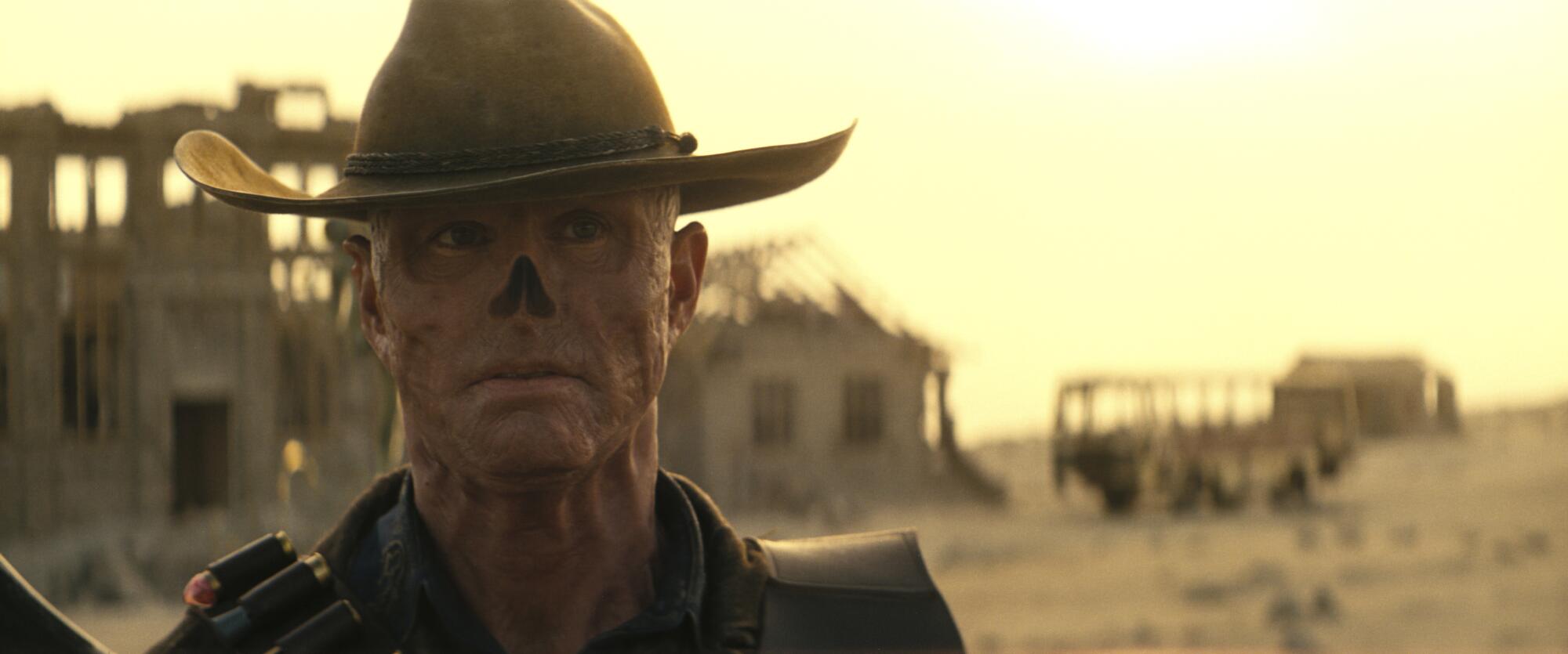 Um ghoul com chapéu de cowboy em uma paisagem desolada.