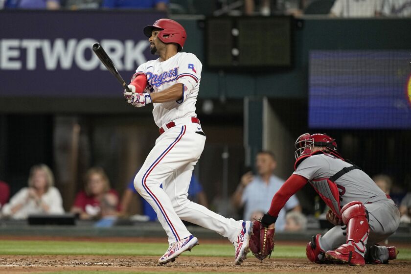 Texas Rangers' Marcus Semien follows through on a double as St. Louis Cardinals catcher Willson Contreras looks on in the fourth inning of a baseball game, Tuesday, June 6, 2023, in Arlington, Texas. (AP Photo/Tony Gutierrez)