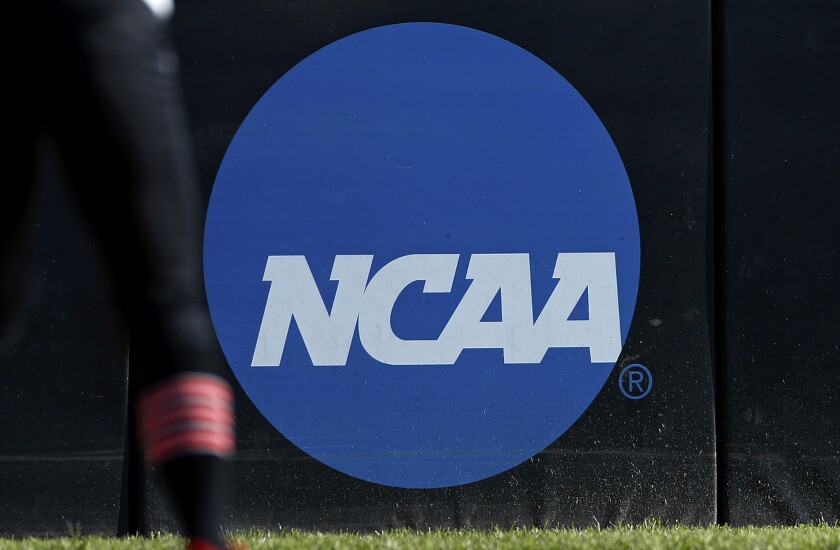 FILE - An athlete stands near the NCAA logo during a softball game in Beaumont, Texas, April 19, 2019. The latest diversity study on FBS hiring finds women and people of color are underrepresented in athletic departments. The report card was issued Wednesday, Jan. 26, 2022, by The Institute for Diversity and Ethics in Sport.(AP Photo/Aaron M. Sprecher, File)