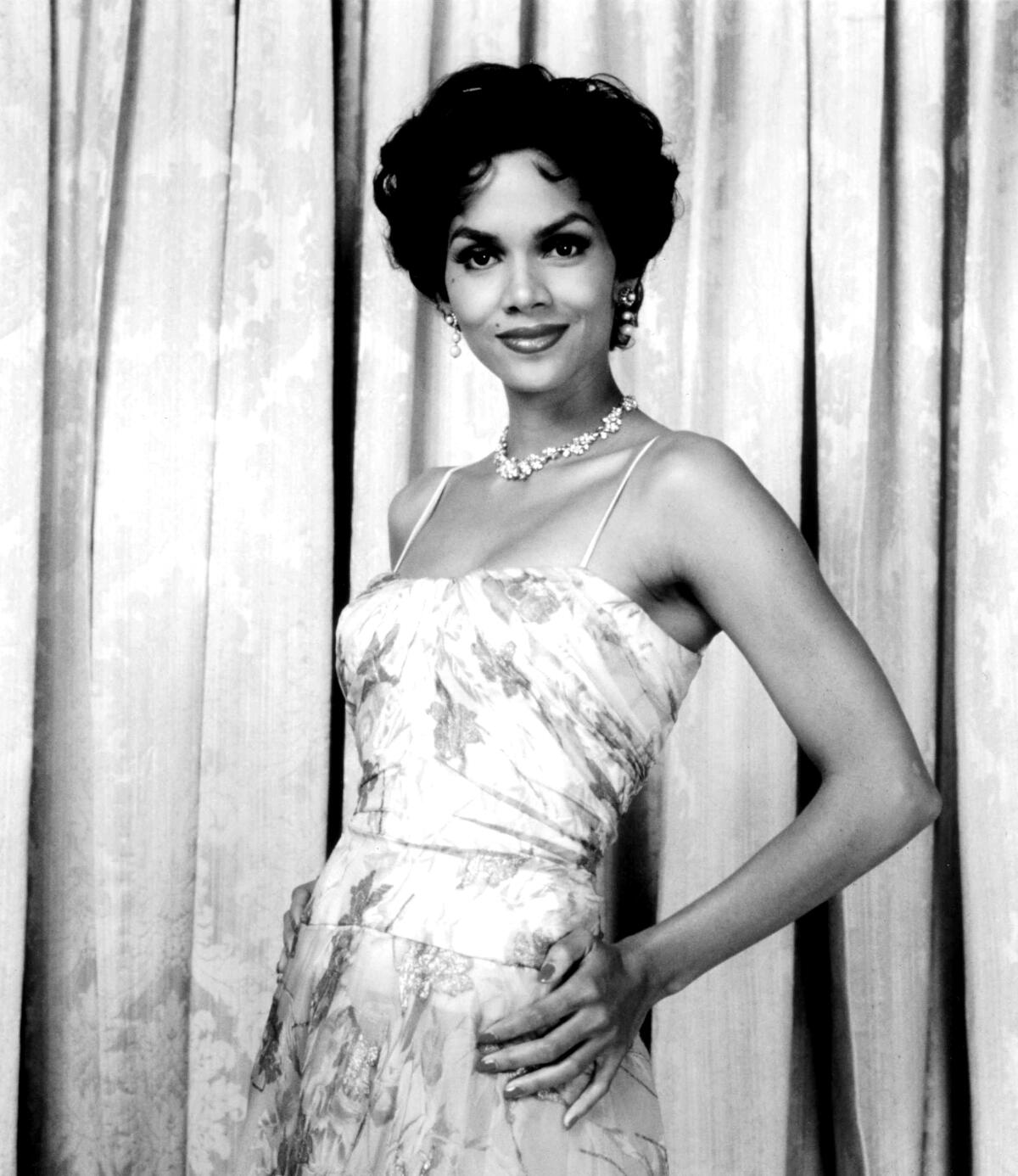 A woman smiles in front of a curtain.