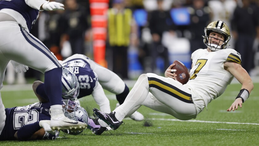 Dallas Cowboys middle linebacker Keanu Neal (42) and Dallas Cowboys defensive end Tarell Basham (93) tackle New Orleans Saints quarterback Taysom Hill (7) during the second half of an NFL football game, Thursday, Dec. 2, 2021, in New Orleans. (AP Photo/Brett Duke)