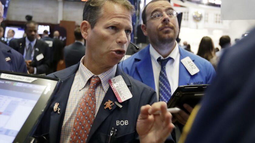 Robert Charmak, left, works with fellow traders on the floor of the New York Stock Exchange on July 11.