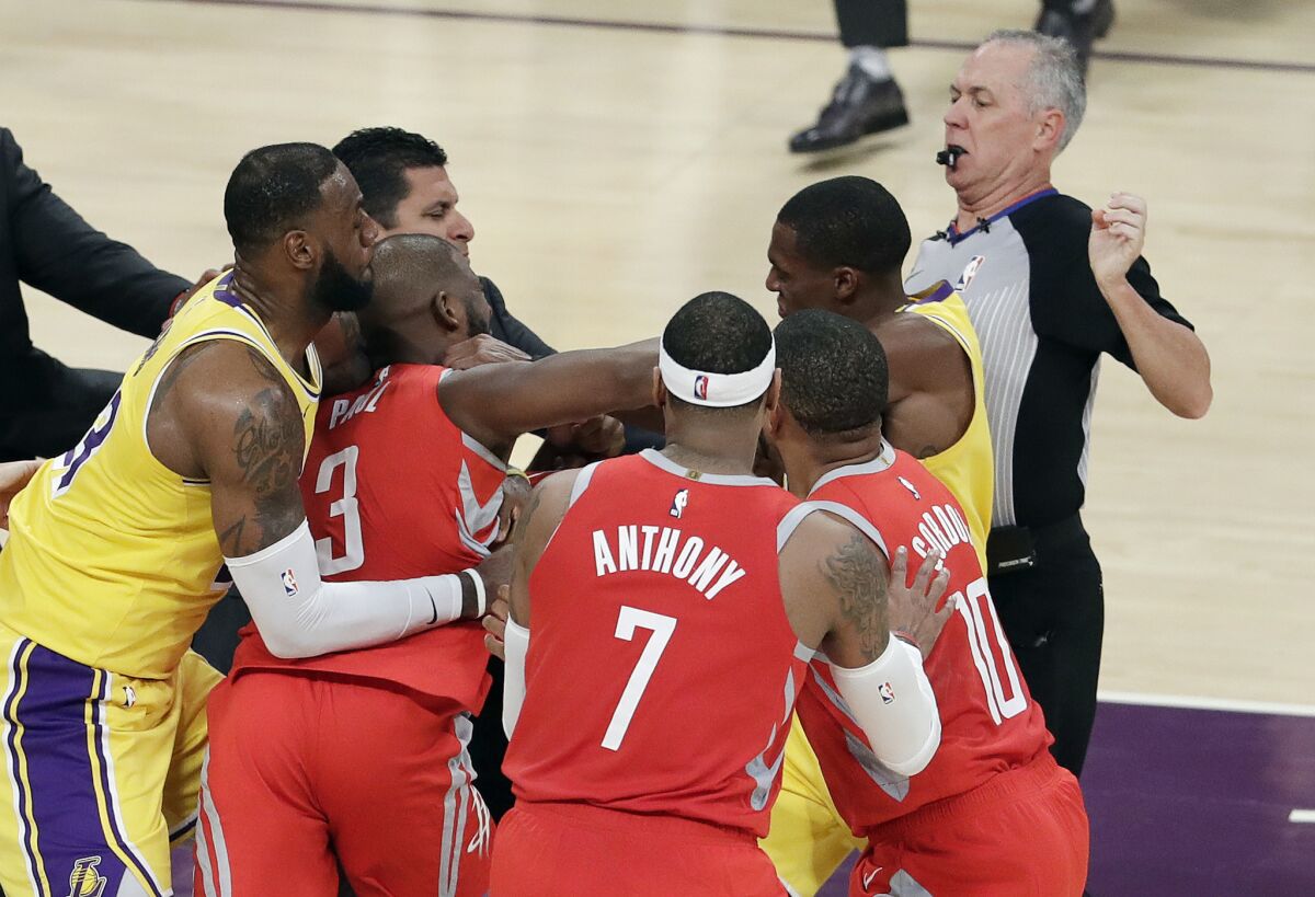 Rockets point guard Chris Paul trades punches with Lakers point guard Rajon Rondo, who is next to the referee.