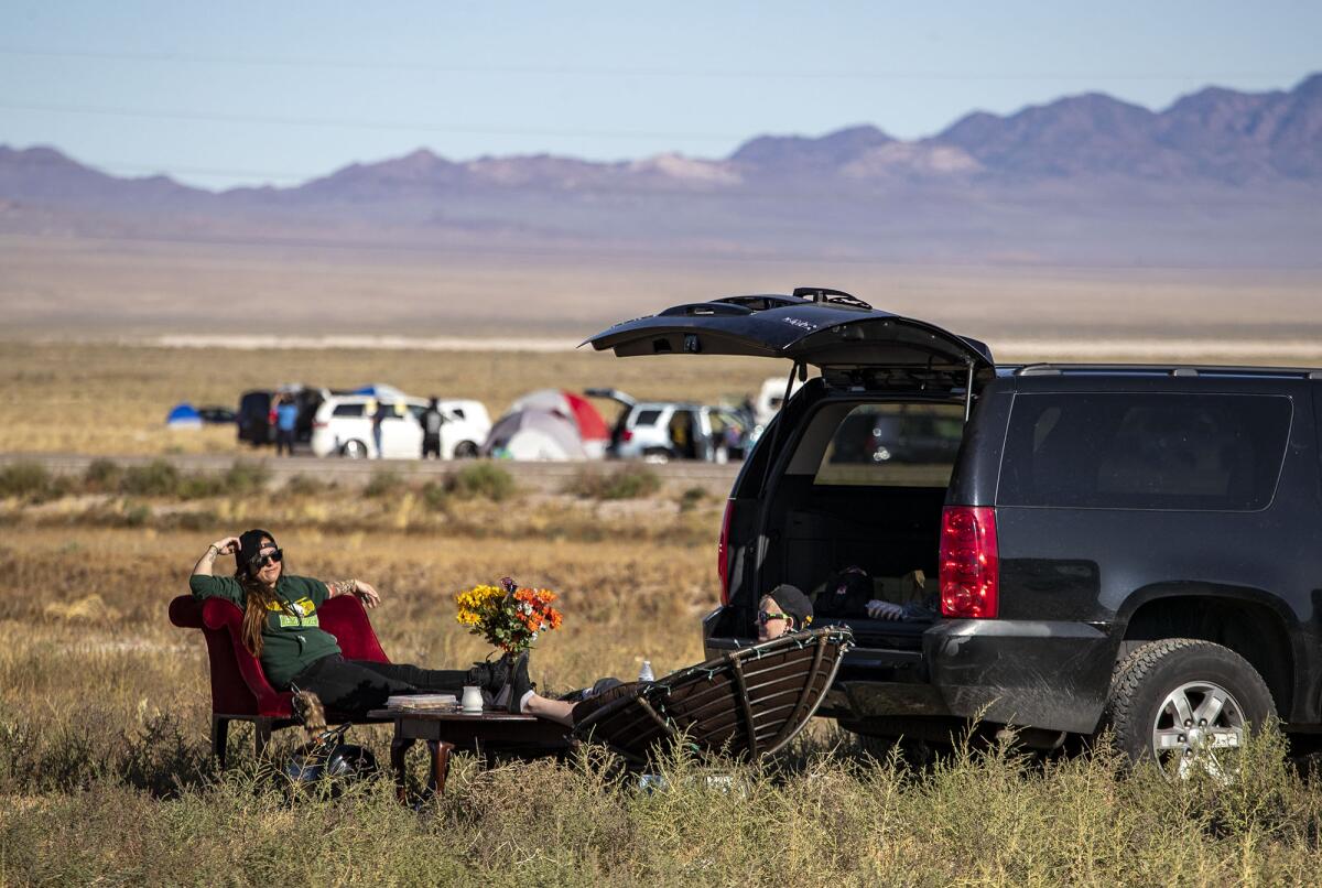 Al carecer de equipo para acampar, Cassie Cazessus, a la izquierda, y Cassandra Steed, a la derecha, trajeron los muebles de su sala de estar para relajarse en Rachel, NV, la ciudad adyacente al Área 51.