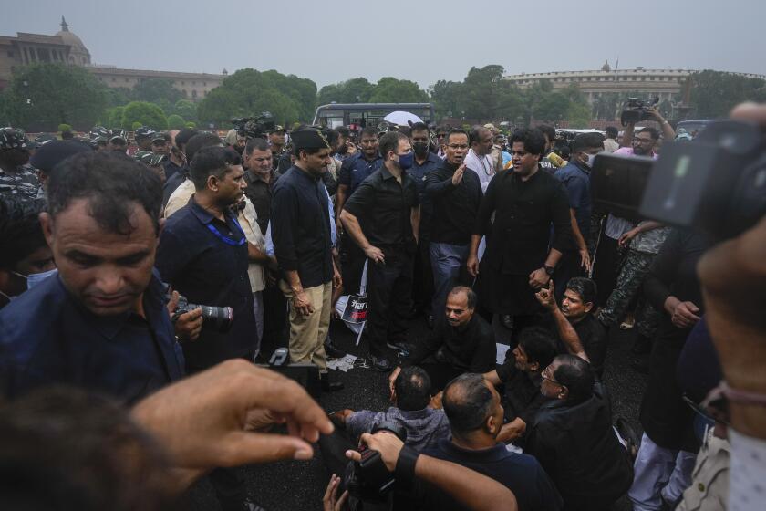 Congress party leader Rahul Gandhi, center in blue mask, and other lawmakers participate in a protest in New Delhi, India, Friday, Aug. 5, 2022. “Democracy is a memory (in India),” Gandhi later tweeted, describing the dramatic photographs that showed him and his party men being briefly detained by police. Gandhi’s statement resonated amid a growing sentiment in the country that India’s democracy, the world’s largest with nearly 1.4 billion people, is in retreat and its democratic foundations are floundering. (AP Photo/Altaf Qadri)