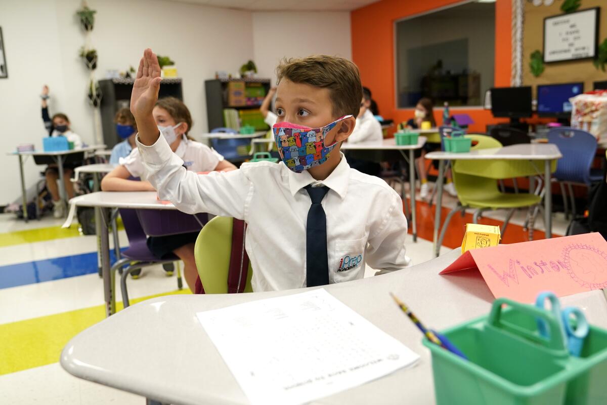 FILE - In this Monday, Aug. 23, 2021, file photo, student Winston Wallace, 9, raises his hand in class at iPrep Academy on the first day of school in Miami. A judge has ruled that Florida school districts may impose mask mandates. Leon County Circuit Judge John C. Cooper on Friday agreed with a group of parents who claimed in a lawsuit that Gov. Ron DeSantis' ban on the mandates is unconstitutional and cannot be enforced. (AP Photo/Lynne Sladky, File)