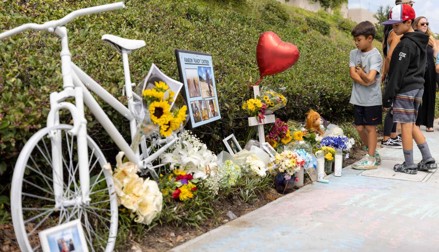 Family and friends visit the ghost bike memorializing Randy Cintron, who was struck and killed in a hit-and-run crash on Jamboree Road in Newport Beach.