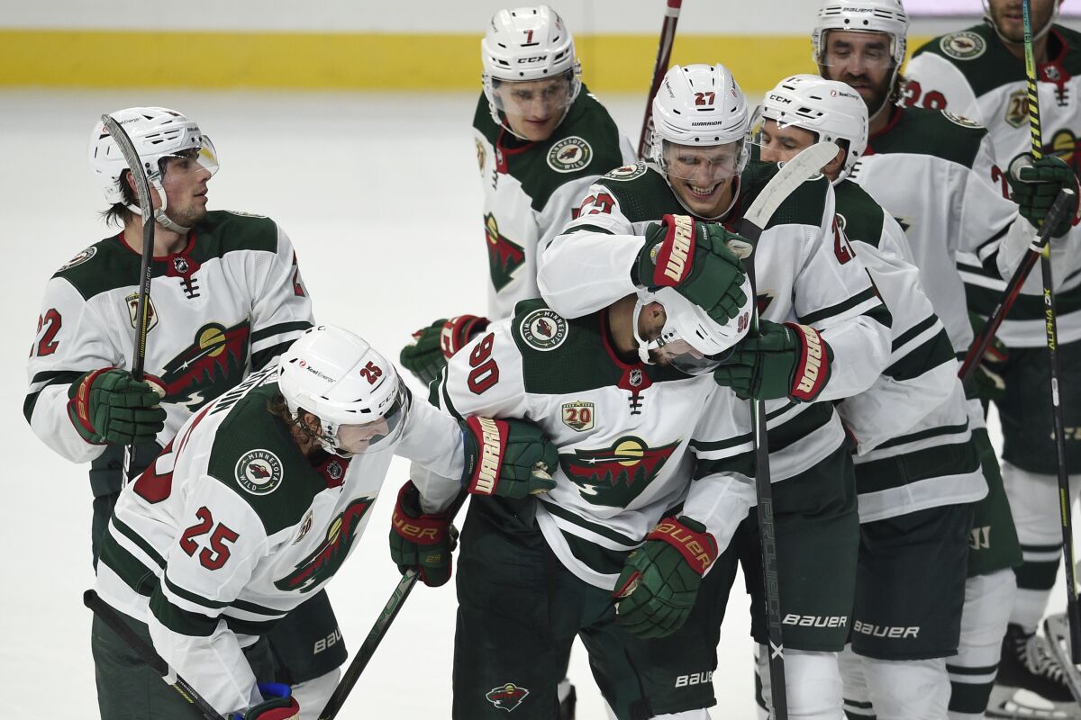 Minnesota Wild players congratulate Marcus Johansson, front center, on his overtime goal in an NHL hockey game against the Los Angeles Kings in Los Angeles, Saturday, Jan. 16, 2021. (AP Photo/Kelvin Kuo)