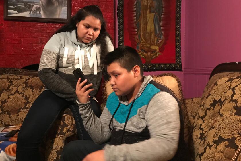 Juana Andres, 12, and Eduardo Andres, 14, take a call from a relative as they wait for news of their mother and father who were detained Wednesday at their workplace in Morton, Miss., by federal immigration officials.