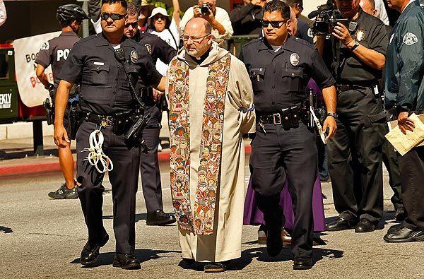 Father Chris Ponnet, director/pastor of the St. Camillus Catholic Center for Pastoral Care is arrested at the conclusion of an Interfaith Communities United for Justice and Peace rally that blocked Los Angeles Street in downtown L..A. The protest marking the 10th anniversary of the war in Afghanistan began at La Placita Church and continued with a march past City Hall to the Federal Building.