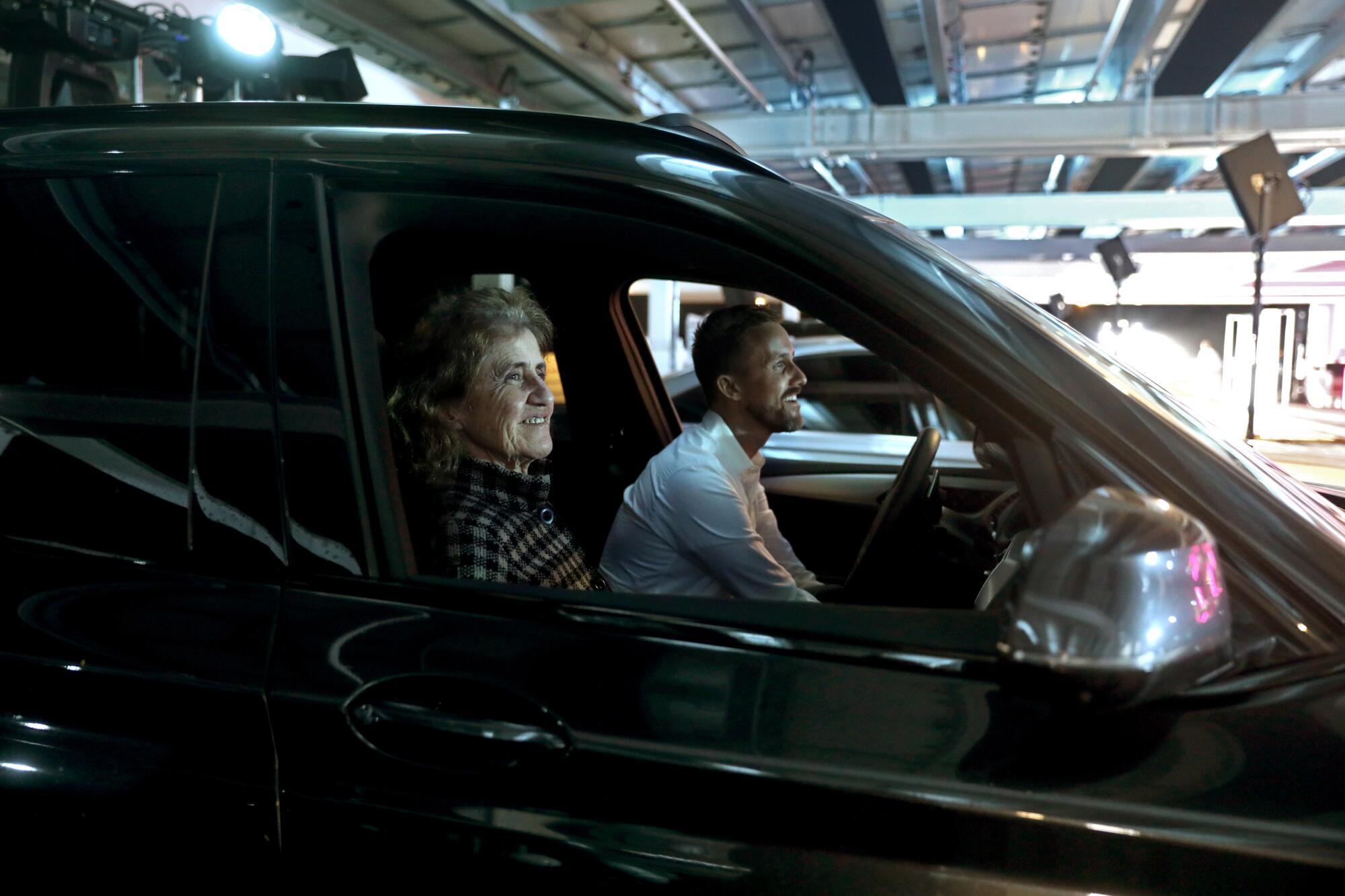 Two people sit in the front seat of a vehicle.