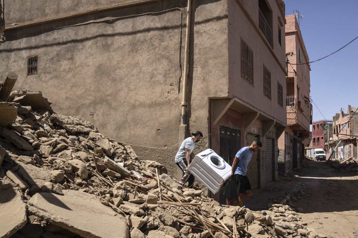 Dos personas recuperan una lavadora de su casa dañada por un sismo