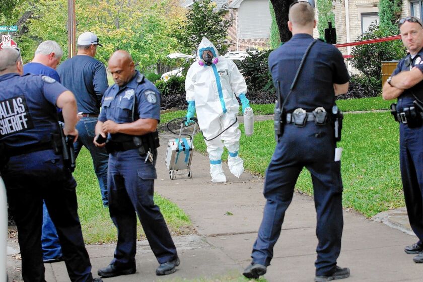 A worker in a protective hazmat suit walks in front of an east Dallas apartment building where a second person diagnosed with the Ebola virus lives. Cleaning crews decontaminated the lawn and surrounding area after the healthcare worker was isolated at a local hospital.