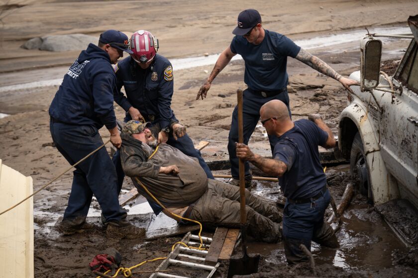 Don Stinson gets rescued from deep mud at his mother's houseboy the Swift Water Rescue Team from the State Office of Emergency Service with the team from Orange County. (Tomas Ovalle / For The Times)
