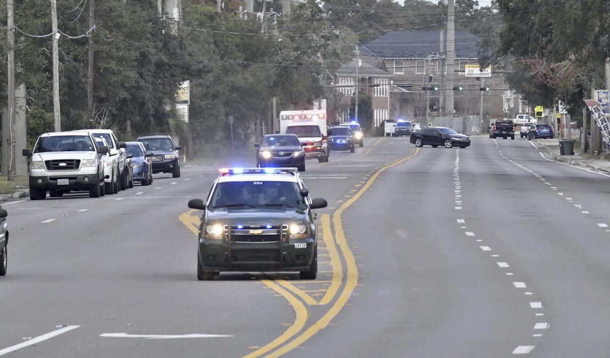 Police cars escort an ambulance