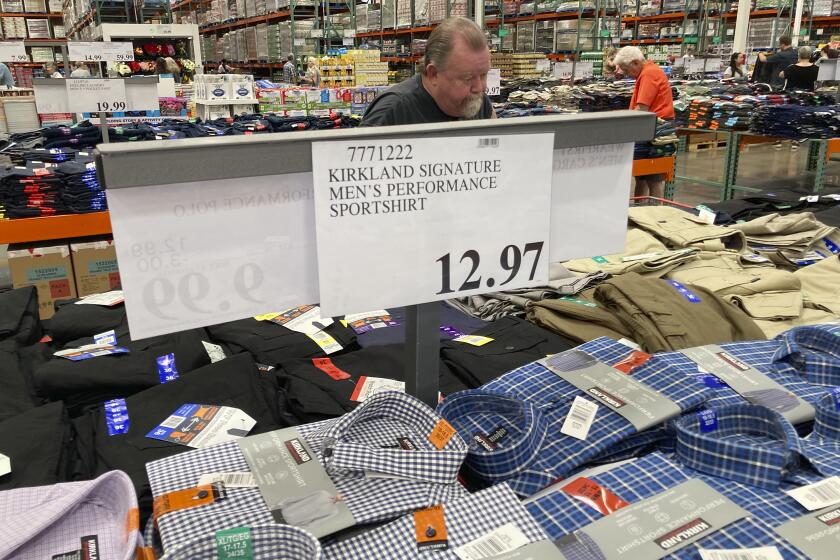 A sign displays the price for shirts as a shopper peruses the offerings at a Costco warehouse on Thursday, June 17, 2021, in Lone Tree, Colo. American consumers faced a third straight monthly surge in princes in June, the latest sign that a rapid reopening of the economy is fueling a pent-up demand for goods and services that in many cases remain in short supply. (AP Photo/David Zalubowski)