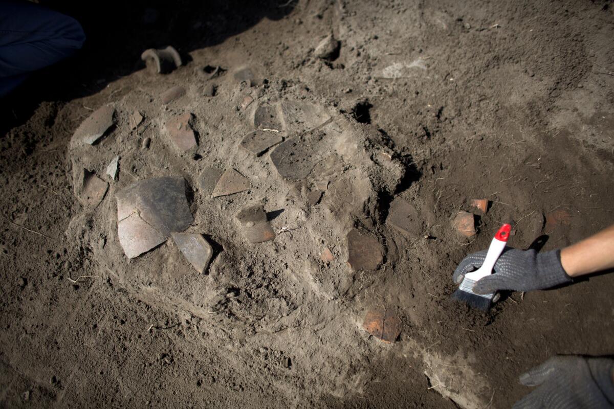 Un trabajador despeja la zona en torno a varios objetos de alfarería en el yacimiento de Zultepec-Tecoaque en el estado de Tlaxcala. A los habitantes de la localidad aliada de los aztecas se los conoce como texcocanos or acolhuas.