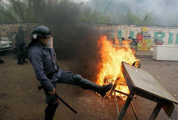 A police officer kicks down a barricade during protests in Sao Paulo's Capao Redondo neighborhood. Police evicted about 800 families from the slum, which squatters have illegally occupied for two years.