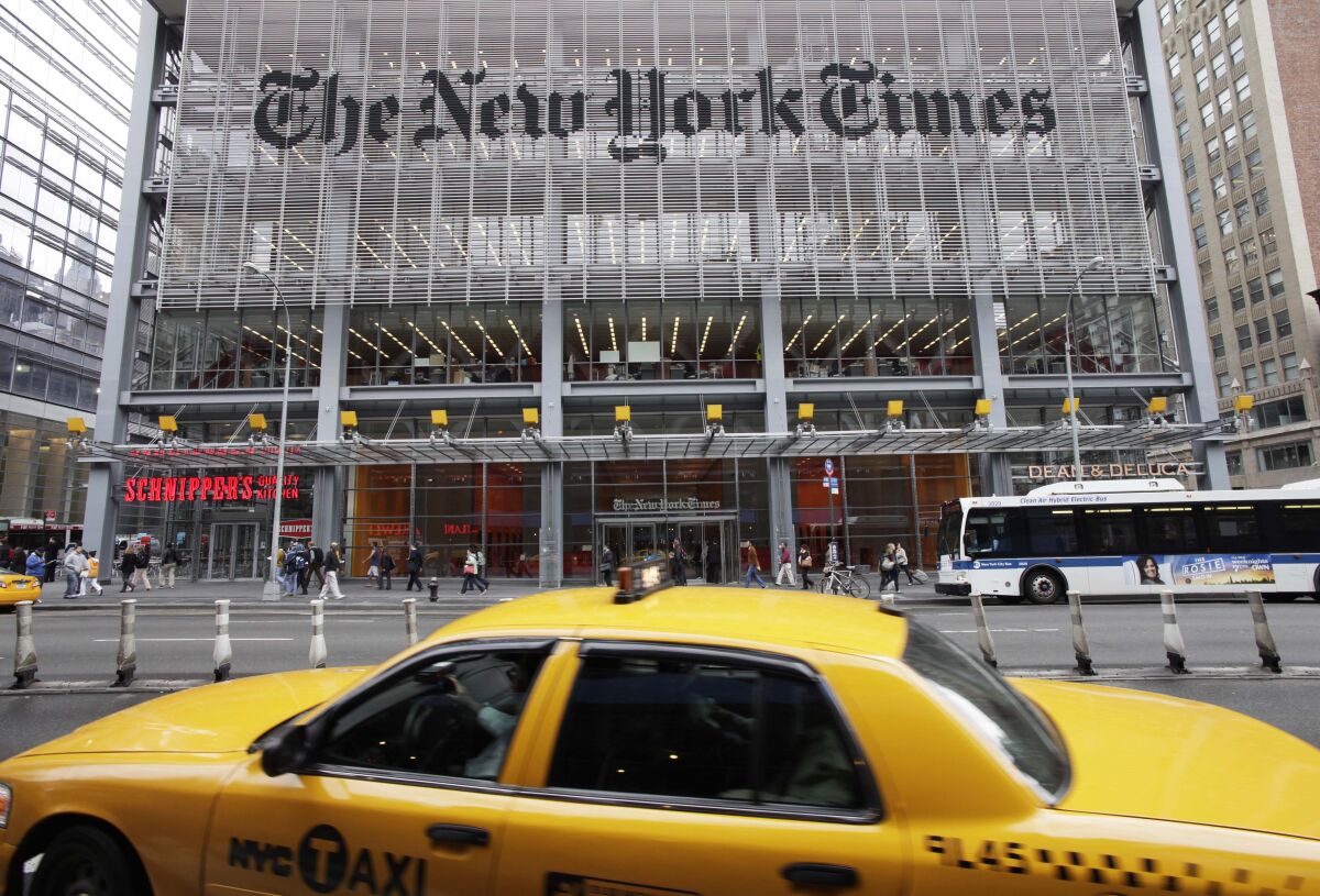The New York Times building in New York in 2019, with people walking in front of it and a taxi in the foreground.