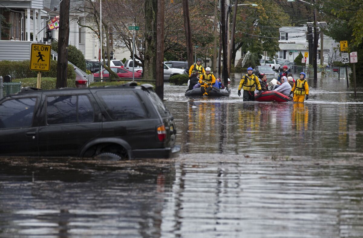 People are rescued by boat on a flooded street in Little Ferry, N.J., in the wake of Hurricane Sandy.