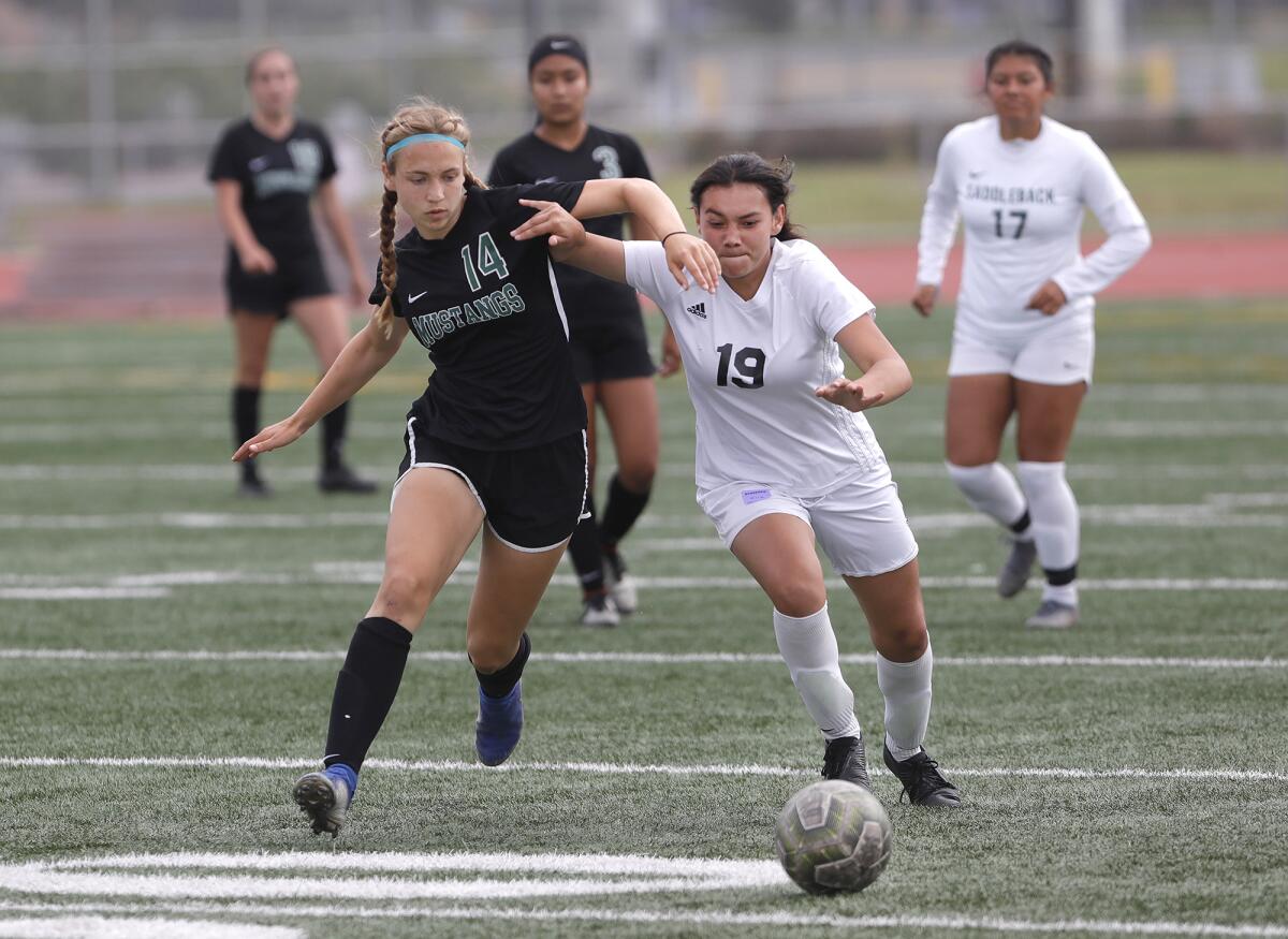 Costa Mesa's Kyra Kirsch (14) battles a Saddleback opponent at midfield for a loose ball in an Orange Coast League match.