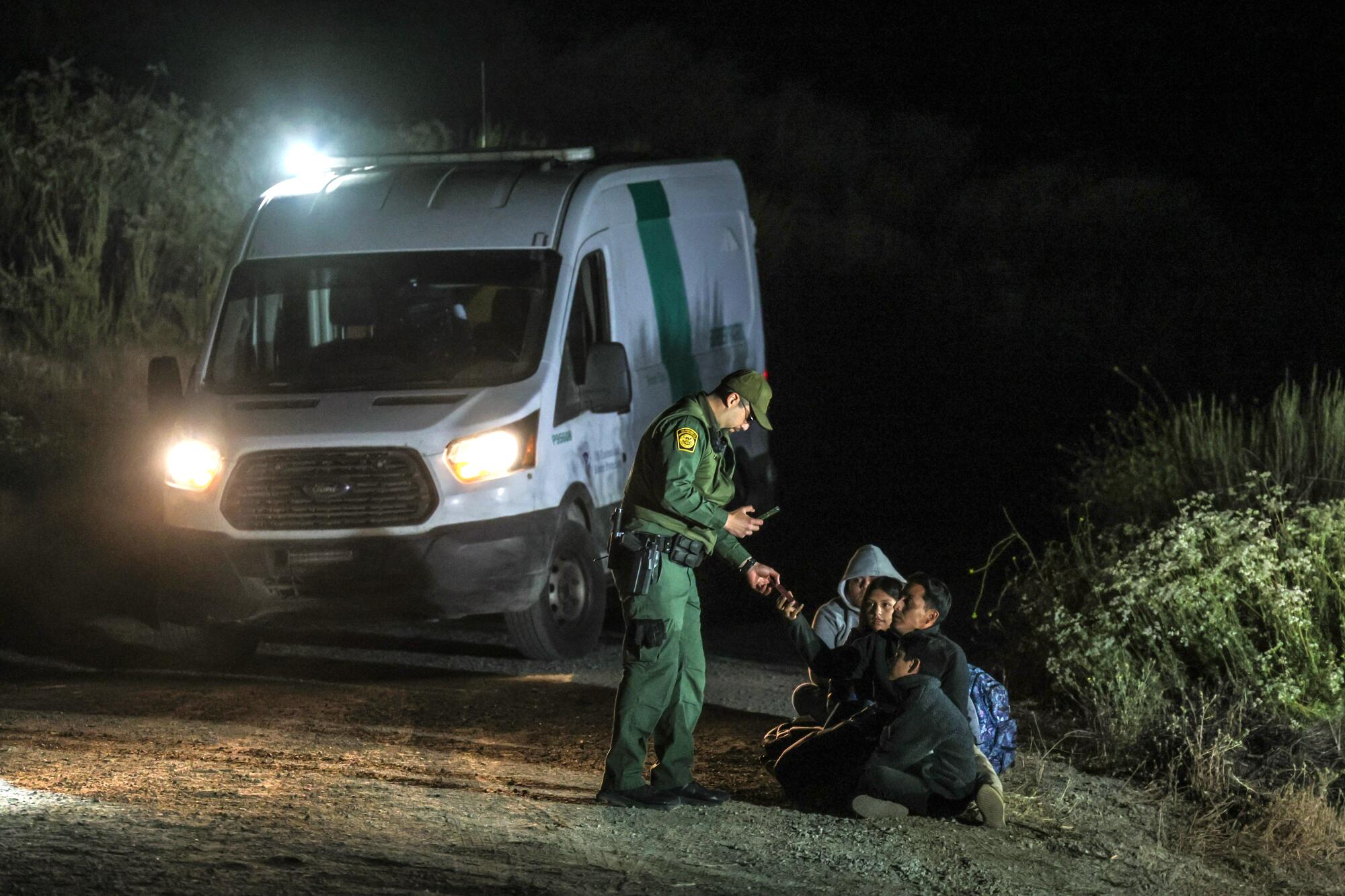     Un agente de la Patrulla Fronteriza documenta a solicitantes de asilo cerca de Campo Rd.  después de cruzar la frontera entre Estados Unidos y México por el monte Cuchoma. 