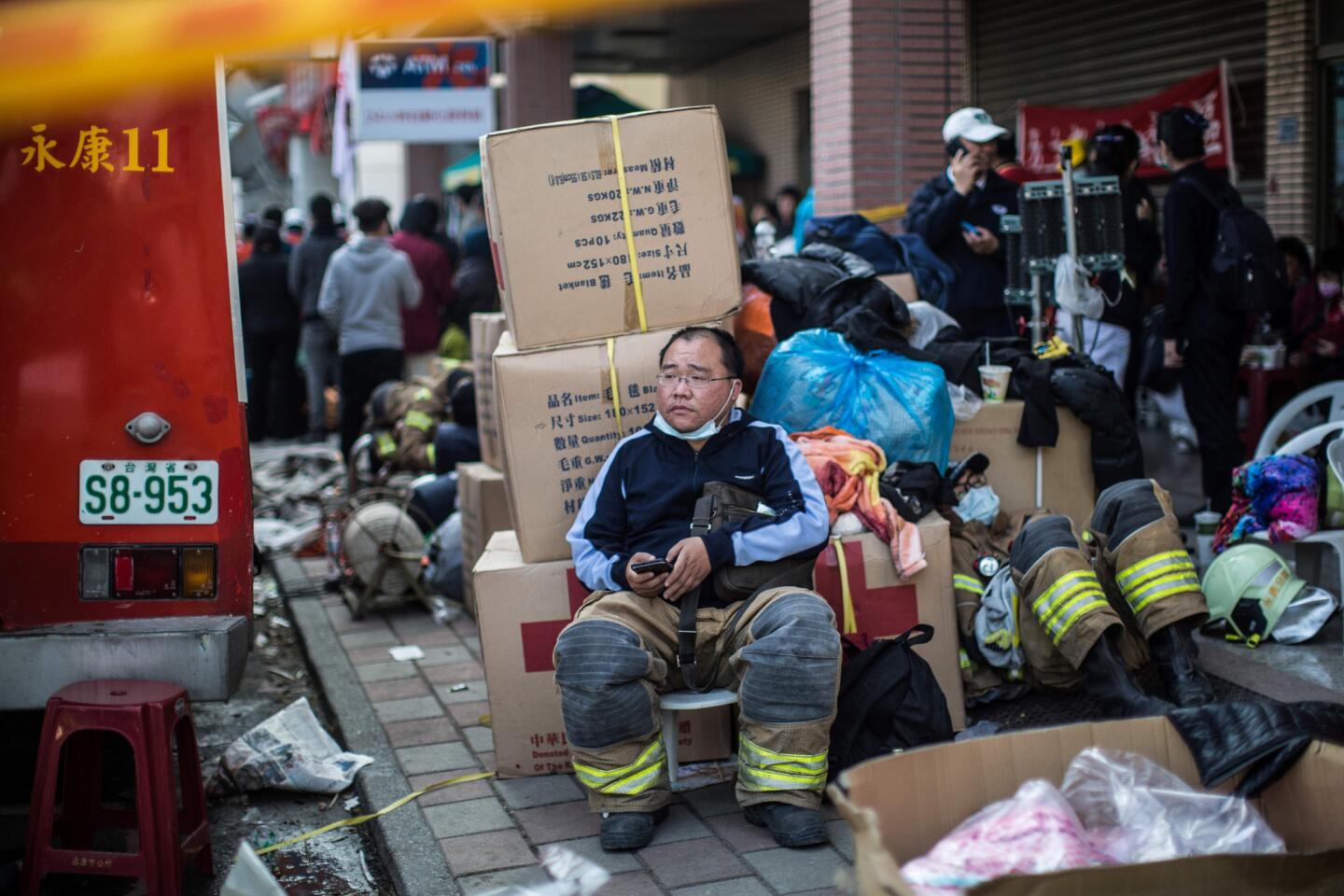 A firefighter rests near a collapsed building in the southern Taiwan city of Tainan.