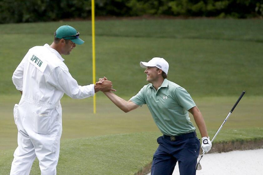 Jordan Spieth celebrates with caddie Michael Greller after he holed a bunker shot for birdie on the fourth hole during the final round of the Masters on Sunday at Augusta National Golf Club.