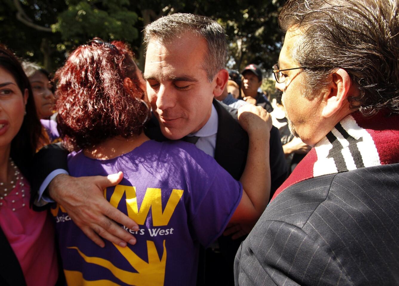 Mayor Eric Garcetti, center, hugs Vella Almada, with the Service Employees International Union on the steps of City Hall after he and Police Department Chief Charlie Beck announce the city's stance regarding jail detentions and federal immigration officials.