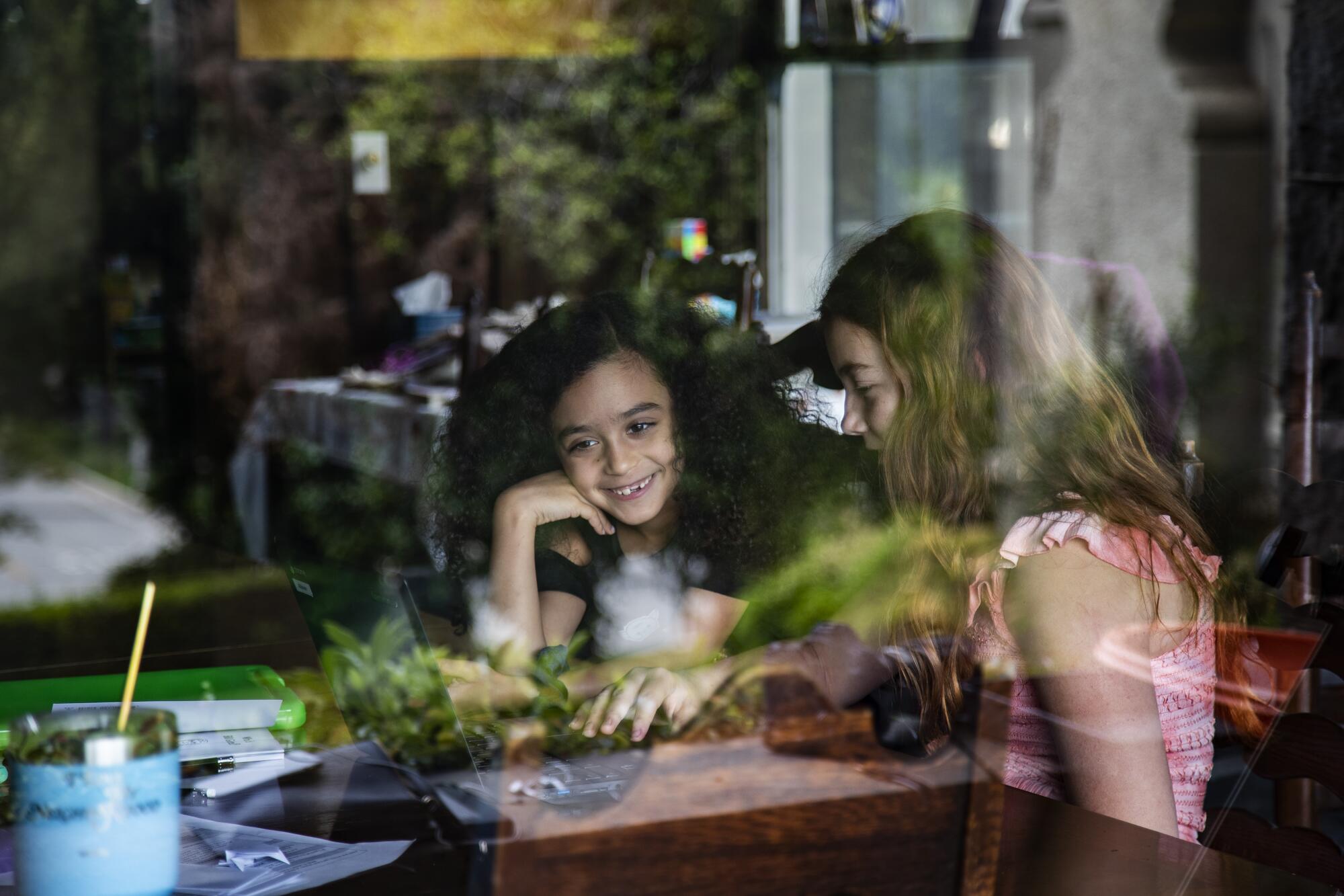 Allison Furbush, left, and Ellie Bristow are seen through a front porch window while teaming up on a science project.