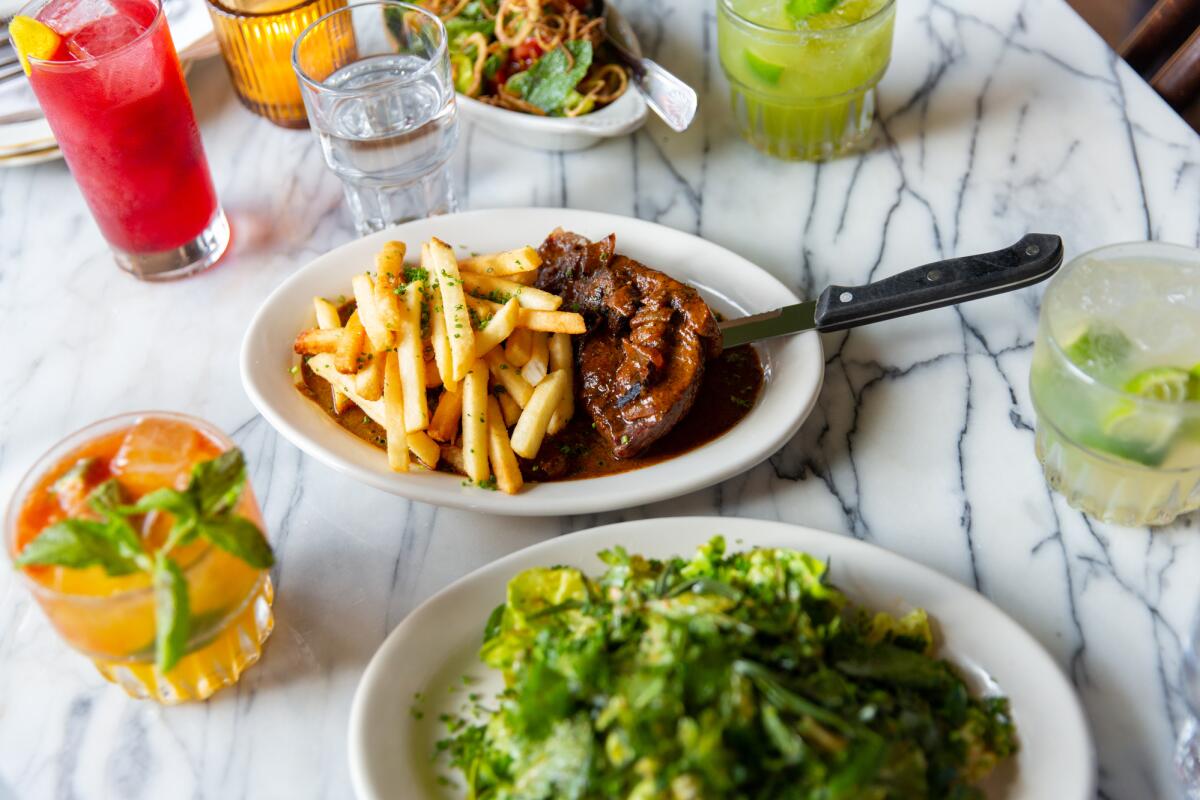 Dishes and cocktails from Nossa Caipirinha Bar including a steak with fries and a salad