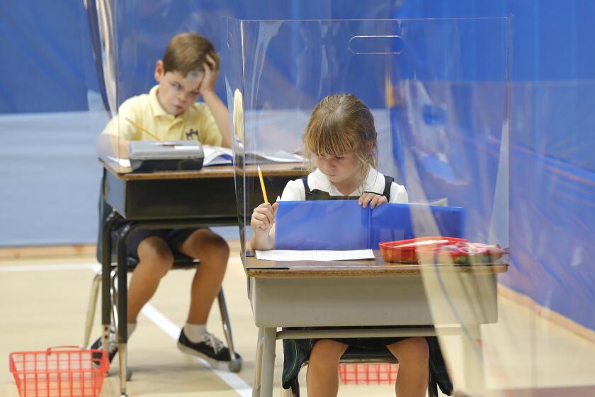 Second graders work on a project behind plexiglass dividers during Isabella Buonanoce's 2nd grade class on day two of re-opening at Saint Joachim Catholic School in Costa Mesa. The school applied for a waiver to allow for the reopening of their TK-6 classes last month, and got clearance to go back to campus on Tuesday.