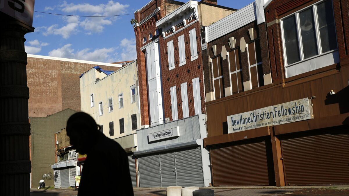 A man walks past vacant storefronts at the Old Town Mall in Baltimore. More than half the neighborhood's residents live in poverty.