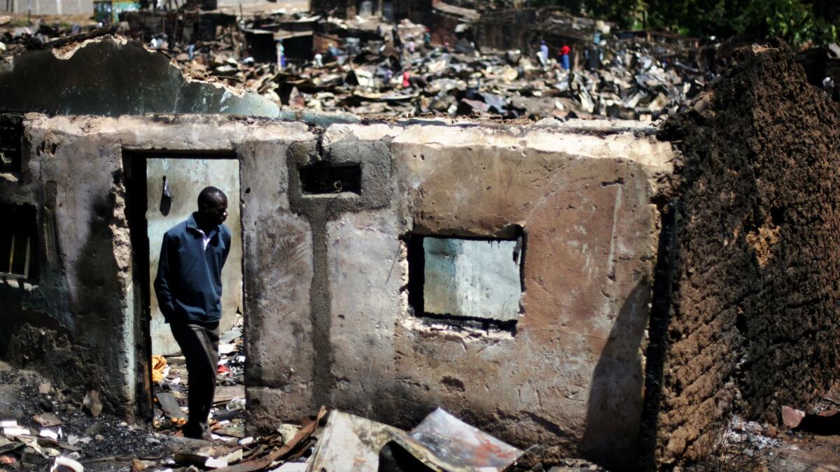 A resident of the Mathare slum in Nairobi, Kenya, looks at the remains of a structure that was set ablaze by demonstrators during civil unrest that erupted after the 2007 presidential election.