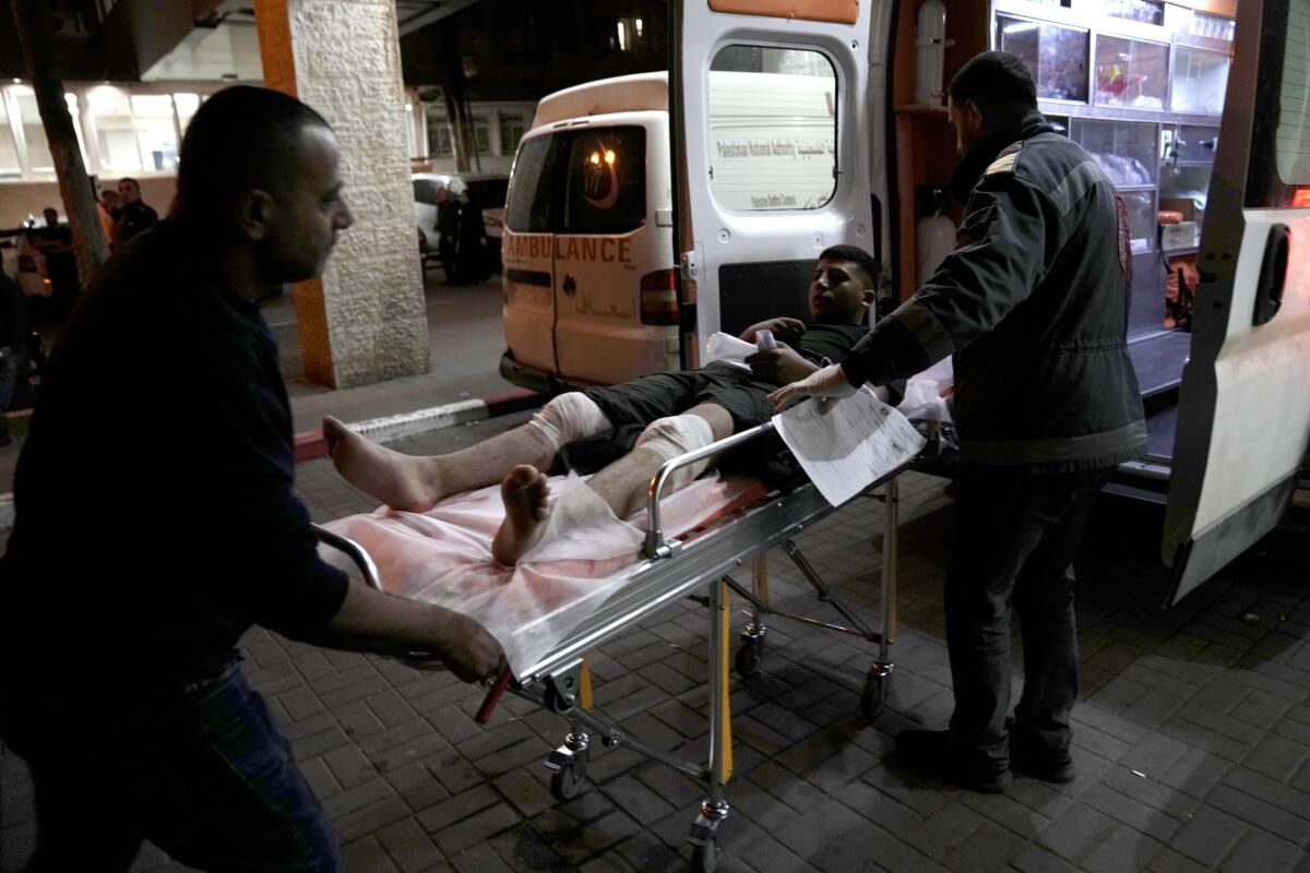A Palestinian man with bandages on both legs is transported on a stretcher at a medical center in the West Bank.