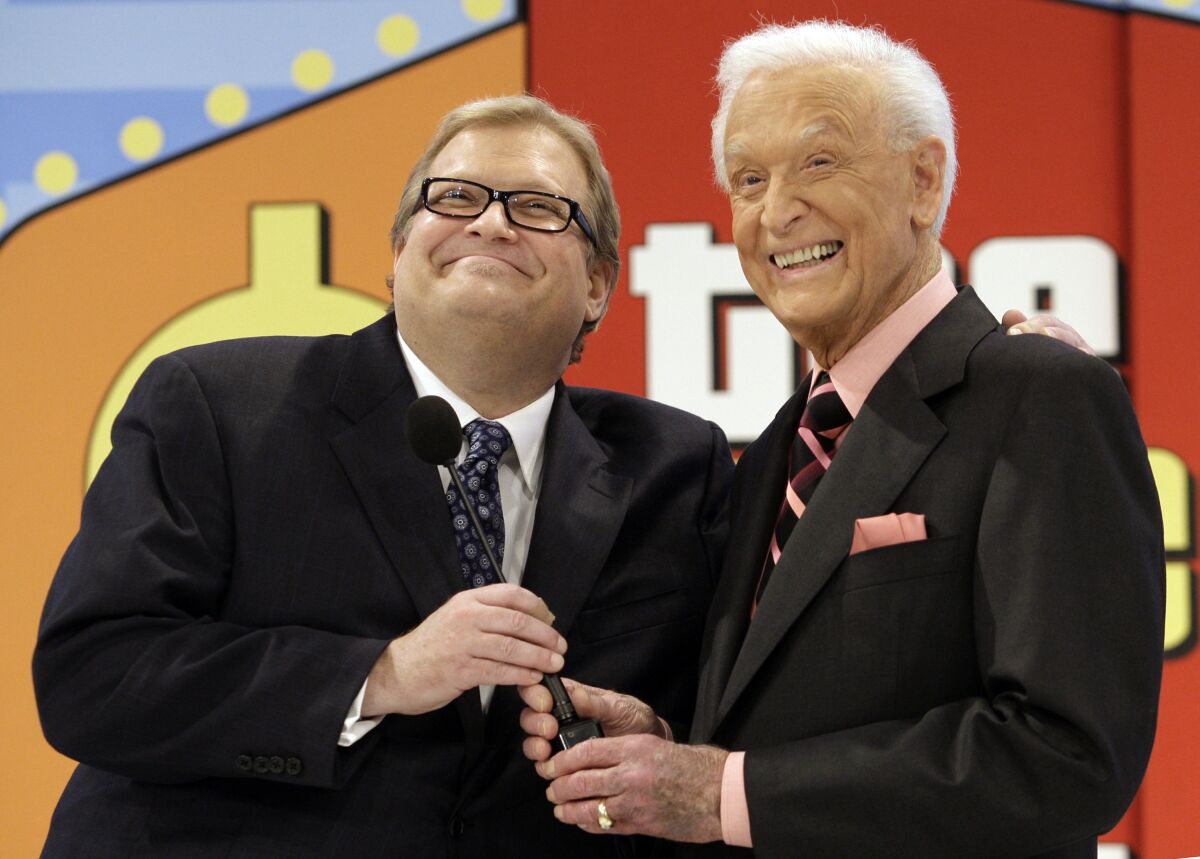 FILE - The Price is Right show host, comedian Drew Carey, left, appears with longtime former host Bob Barker at the CBS Studio Center in Los Angeles on March 25, 2009. Barker, who retired and passed the microphone off to Carey, appeared on the show to promote his autobiography, "Priceless Memories." The longest-running game show in television history is celebrating it’s 50th season. (AP Photo/Damian Dovarganes, File