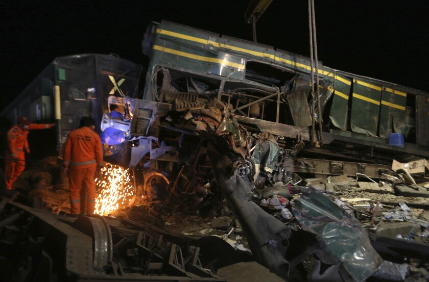 Railway workers near crumpled train car