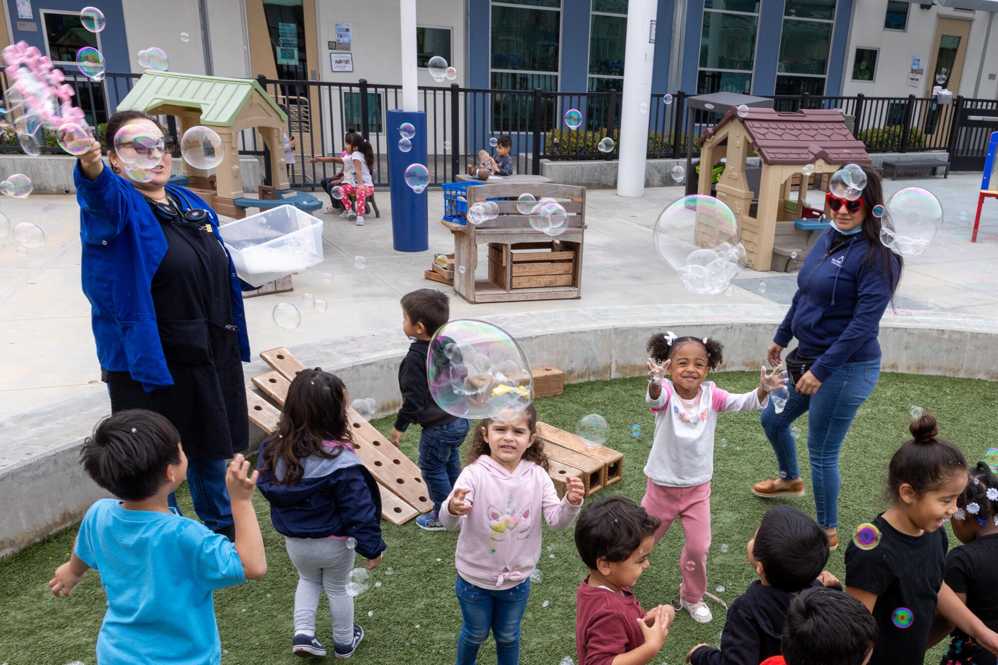 Students play with bubbles on a playground.