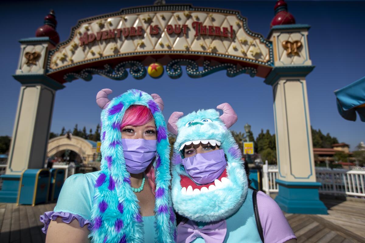 Two women in Sulley costumes stand at an entrance to Pixar Pier. 