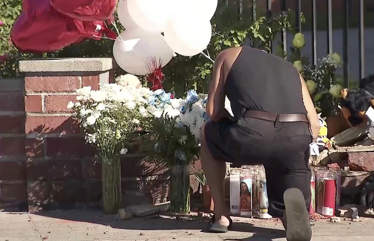 A man kneels in front of a memorial