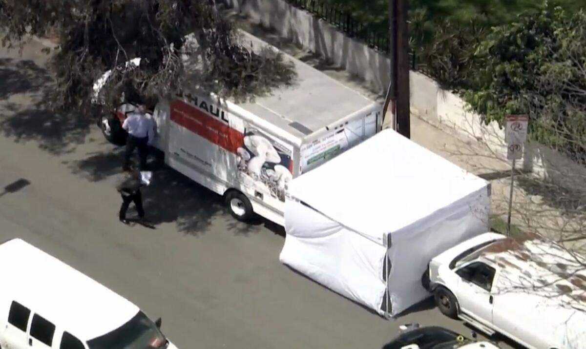 A white tent shields the back of a U-Haul trucked parked on a residential street