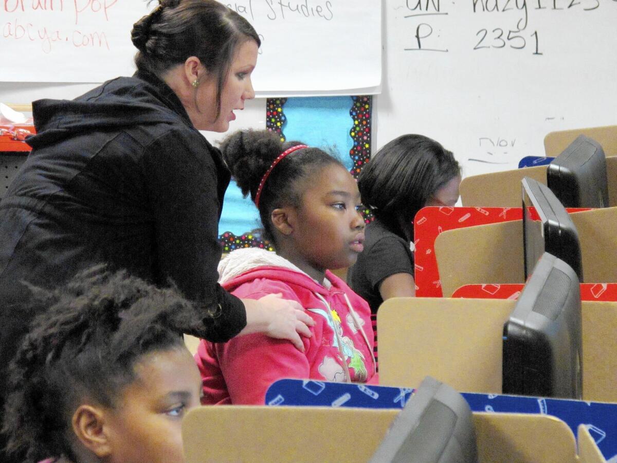 Teacher Angela Wathanacharoen helps fourth-grader Janae Dale with a writing and computer lesson at Frank Rushton Elementary School in Kansas City, Kan. The school joined others in suing the state over a lack of education funding.