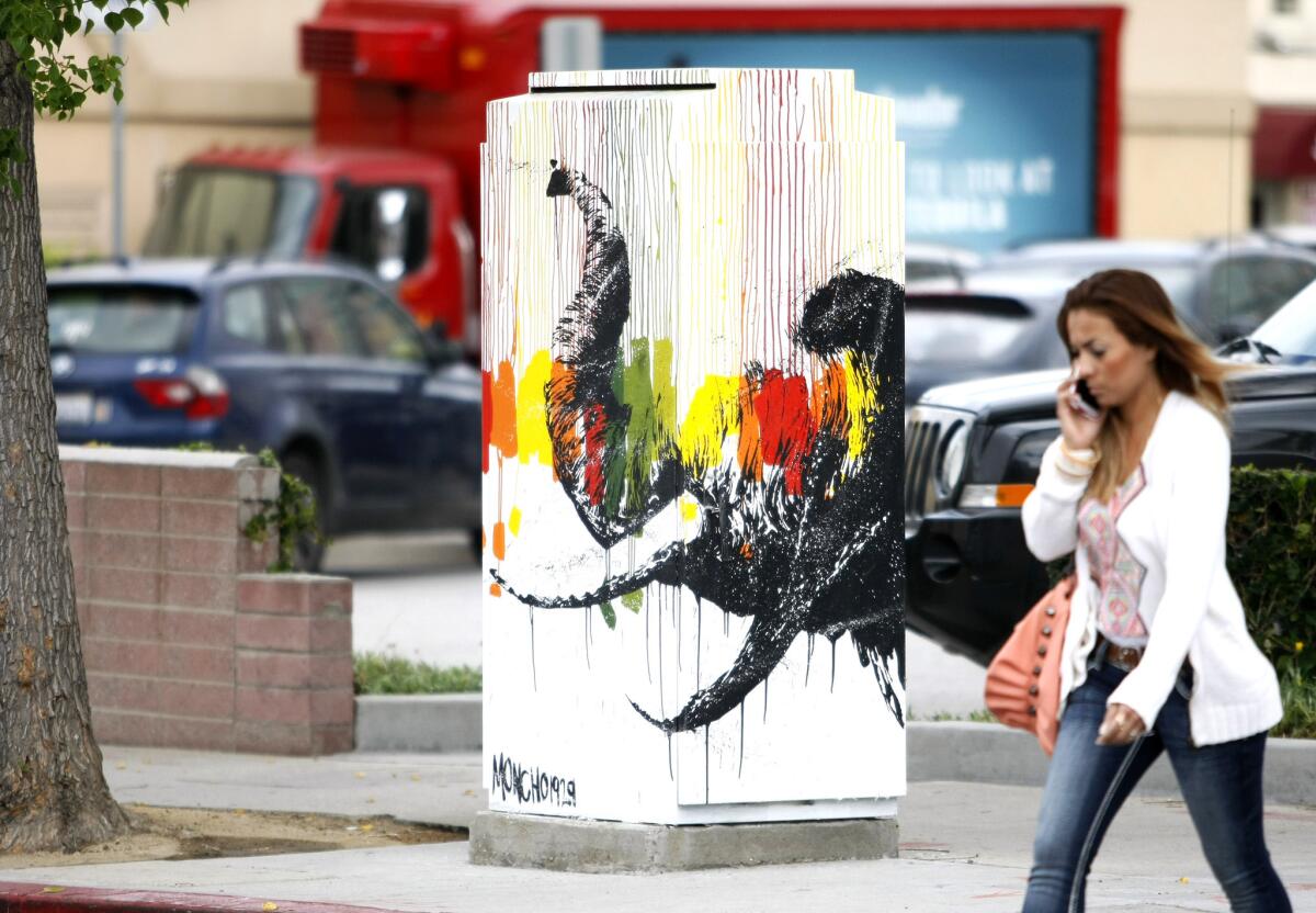 A woman walks past a utility box mural painted with what looks like a colorful elephant at California and Maryland in Glendale on Wednesday, May 21, 2014. The program was sponsored by the Arts & Culture Commission and artists painted 26 utility box murals around Brand Blvd. in Glendale on Saturday, May 17, 2014. The program is being expanded to Montrose.