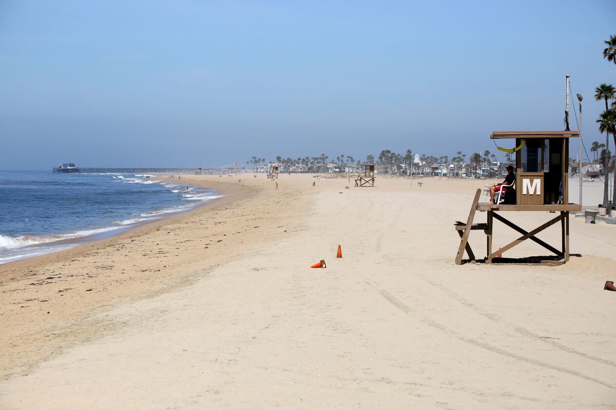 A city lifeguard keeps an eye on the few visitors to the beach next to the Balboa Pier in Newport Beach on May 6.